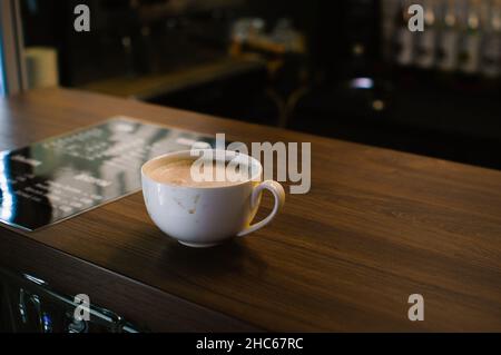 Dirty white coffee cup stands on the wooden counter of a coffee shop Stock Photo