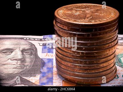 Closeup shot of the stack of metal US One dollars on 100$ US Note bill on isolated black background Stock Photo