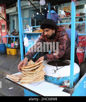 Kabul, Afghanistan. 24th Dec, 2021. An Afghan man cooks Bollani, a local traditional food in Kabul, capital of Afghanistan, Dec. 24, 2021. TO GO WITH 'Feature: Afghans still uneasy as poverty soars despite end of war' Credit: Kabir/Xinhua/Alamy Live News Stock Photo