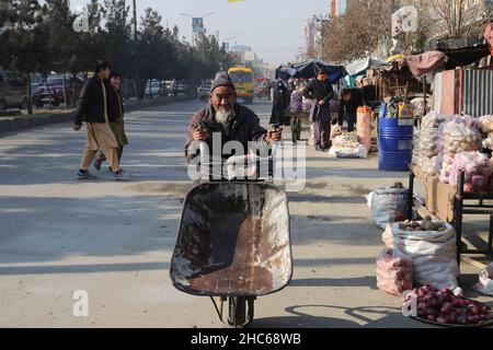 Kabul, Afghanistan. 24th Dec, 2021. An Afghan man pushes a handcart in Kabul, capital of Afghanistan, Dec. 24, 2021. TO GO WITH 'Feature: Afghans still uneasy as poverty soars despite end of war' Credit: Kabir/Xinhua/Alamy Live News Stock Photo