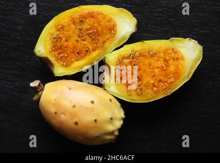 Photography of two prickly pears, one whole the other cut on slate background for food illustrations / prickly pear also known as opuntia scheerii  fr Stock Photo