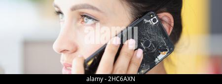 Woman is talking on broken black smartphone closeup Stock Photo