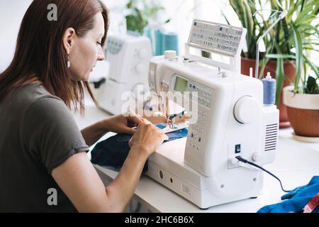 Reuse, repair, upcycle. Denim upcycling ideas, repair and using old jeans. Close-up of sewing machine with shabby, old, torn denim jeans fabric Stock Photo