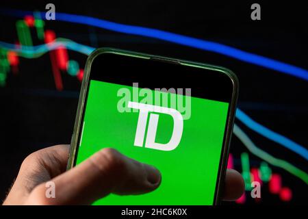 China. 09th Dec, 2021. In this photo illustration the Canadian multinational banking and financial services corporation Toronto Dominion Bank TD logo seen displayed on a smartphone with an economic stock exchange index graph in the background. (Photo by Budrul Chukrut/SOPA Images/Sipa USA) Credit: Sipa USA/Alamy Live News Stock Photo