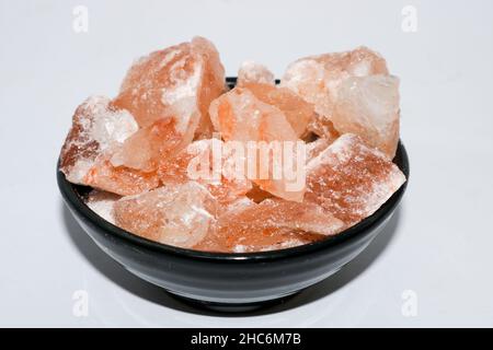 Close up shot of pink himalayan salt blocks in black bowl. Stock Photo