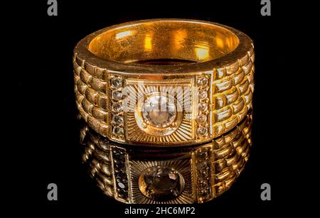 Gold ring with a diamond in the center on a black surface Stock Photo