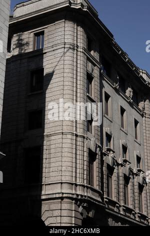 Vertical low angle view of a grey brick building under sunlight and shadows Stock Photo