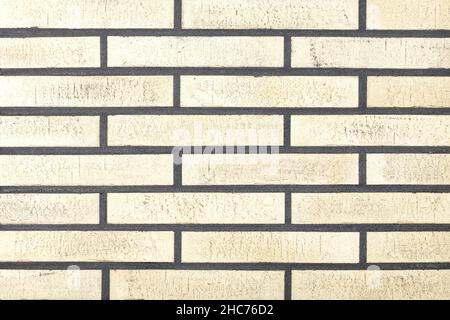 The background and texture of the wall are lined with light beige oblong bricks with even cement joints. Stock Photo