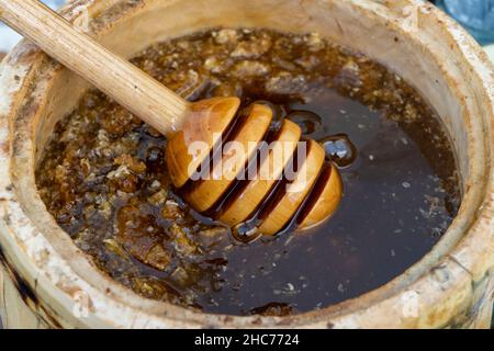 Honey spoon buried in a barrel of fragrant fresh honey. Close-up. Stock Photo
