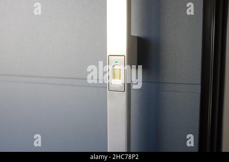 Closeup of a metal handle on a door with a fingerprint reader on it Stock Photo
