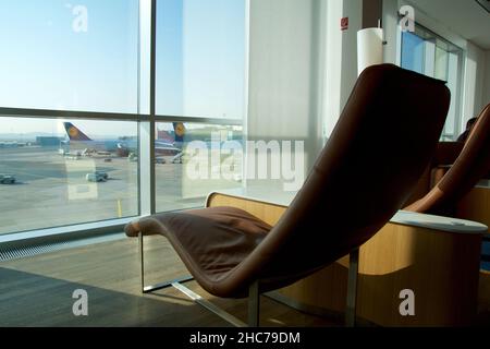 FRANKFURT, GERMANY - 11 NOV 2017: Comfortable lounge chair upholstered in light brown leather in the airport frequent flyer lounge with a view of the Stock Photo