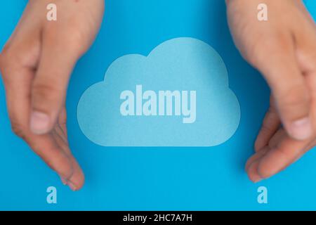 Top view of male hands with a paper-made cloud isolated on a blue background Stock Photo