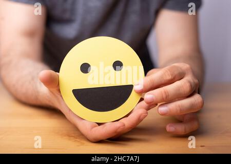 Close-up shot of a hand holding a happy expression emotion smiley on a yellow paper Stock Photo