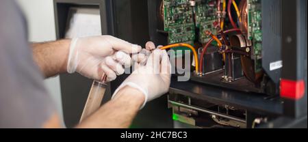 Closeup detail view of electrical engineer operator repairs large premium industrial printer and plotter machine in digital printshop office Stock Photo
