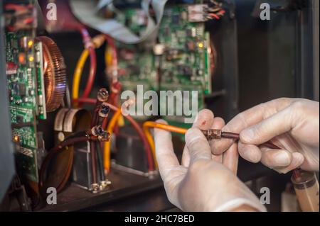Closeup detail view of electrical engineer operator repairs large premium industrial printer and plotter machine in digital printshop office Stock Photo