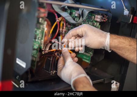 Closeup detail view of electrical engineer operator repairs large premium industrial printer and plotter machine in digital printshop office Stock Photo