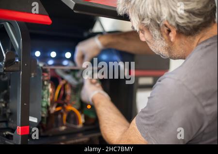 Closeup detail view of electrical engineer operator repairs large premium industrial printer and plotter machine in digital printshop office Stock Photo