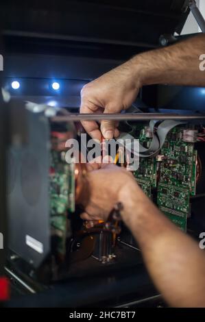 Closeup detail view of electrical engineer operator repairs large premium industrial printer and plotter machine in digital printshop office Stock Photo