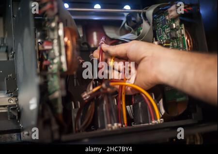 Closeup detail view of electrical engineer operator repairs large premium industrial printer and plotter machine in digital printshop office Stock Photo