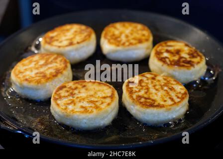 Cottage cheesecakes are fried in a frying pan. The process of cooking delicious homemade food. cheese pancakes or syrniki. Stock Photo