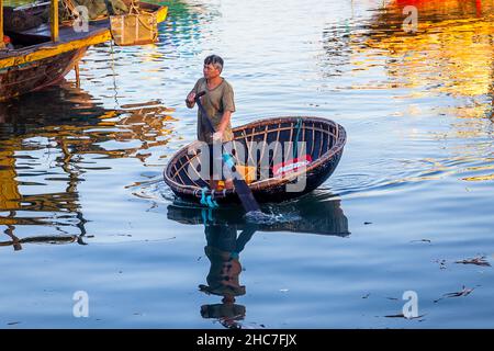 A man in a round basket boat coming ashore after night fishing. Stock Photo