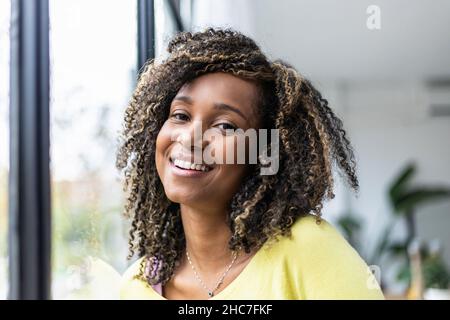 Brazilian young woman with curly hair looking at camera close to the window Stock Photo