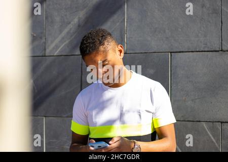 young latino guy with cell phone on the street Stock Photo