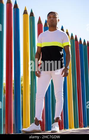 Vertical portrait of a young latin guy on the street leaning against a wall Stock Photo