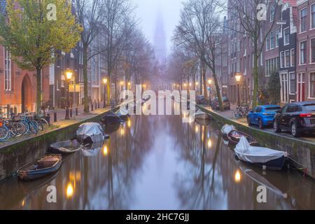 Evening Amsterdam canal Groenburgwal with Zuiderkerk, southern church, in the morning mist, Holland, Netherlands. Stock Photo