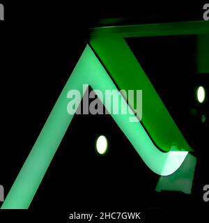 Green light falling on the angle of a wall on dark background Stock Photo