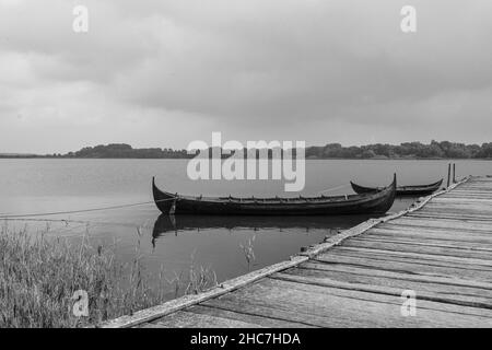 Grayscale shot of a wooden boat by the dock on the coastline Stock Photo