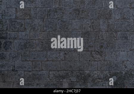 Irregular dark gray bricks dirty and wet wall background  Stock Photo