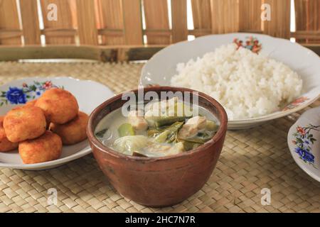 Sayur Lodeh or Vegetables with Coconut Milk Soup. Traditional Indonesian Culinary Food from Java in Traditional Bowl served on Bamboo Table. Selective Stock Photo