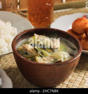 Sayur Lodeh or Vegetables with Coconut Milk Soup. Traditional Indonesian Culinary Food from Java in Traditional Bowl served on Bamboo Table. Selective Stock Photo