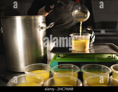 Food delivery in the restaurant. The chef prepares food in the restaurant and prepares it in disposable dishes on the scales, weighing the required Stock Photo