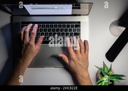 A man works at a computer at night, top view. Stock Photo