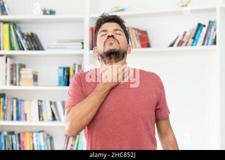 Mature adult mexican man with throat pain indoors at home Stock Photo