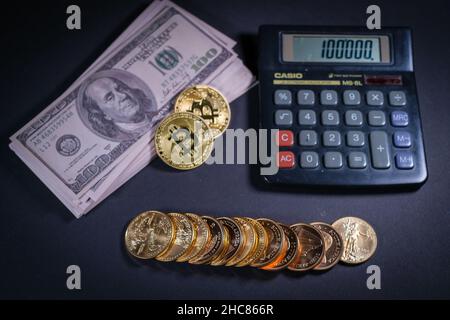 gold coins are lying next to a stack of dollar banknotes, bitcoin and a calculator Stock Photo