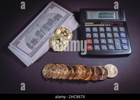 gold coins are lying next to a stack of dollar banknotes, bitcoin and a calculator Stock Photo