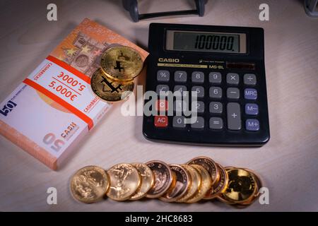 gold coins are lying next to a stack of euro banknotes, bitcoin and euín calculator Stock Photo
