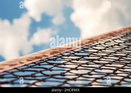 Тennis sport net against the bright blue sky with clouds. Stock Photo