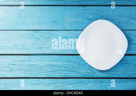 An empty round white plate on a blue wooden table. Top view Stock Photo