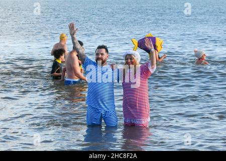 Paignton, Devon, UK.  26th December 2021.  UK Weather.  Swimmers in festive fancy dress take to the sea on Boxing Day for the Lion’s Club Walk in to the Sea at the beach at Paignton in Devon on an unseasonably  warm sunny day.  Picture Credit: Graham Hunt/Alamy Live News Stock Photo