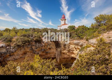 Historical lighthouse surrounded by trees at Praia do Carvoeiro in Algarve, Portugal Stock Photo