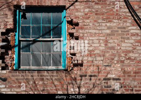 Colorful window with broken pane set in damaged brick wall with negative space for copy Stock Photo