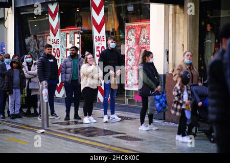 Boxing Day shoppers queue to enter shops in the centre of Cardiff, Wales, as new Covid-19 rules come into force. Groups of no more than six people will be allowed to meet in pubs, cinemas and restaurants in Wales, with two-metre social distancing being required in public premises and offices. Picture date: Sunday December 26, 2021. Stock Photo