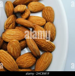 peeled almonds close up on white plate Stock Photo