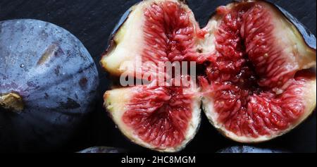 An open fresh red fig and a closed one on slate for food banner Stock Photo