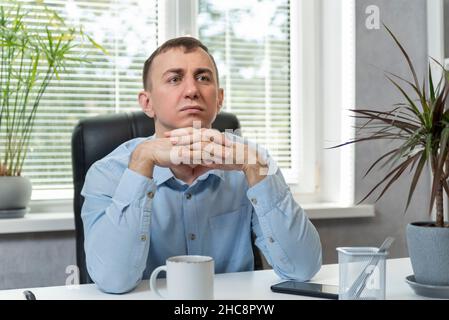 Brooding young man in the office. Portrait of middle-aged director in his own cabinet Stock Photo