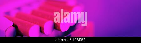 Open pack of cigarettes with close-up of several stretched cigarettes in neon light. Stock Photo
